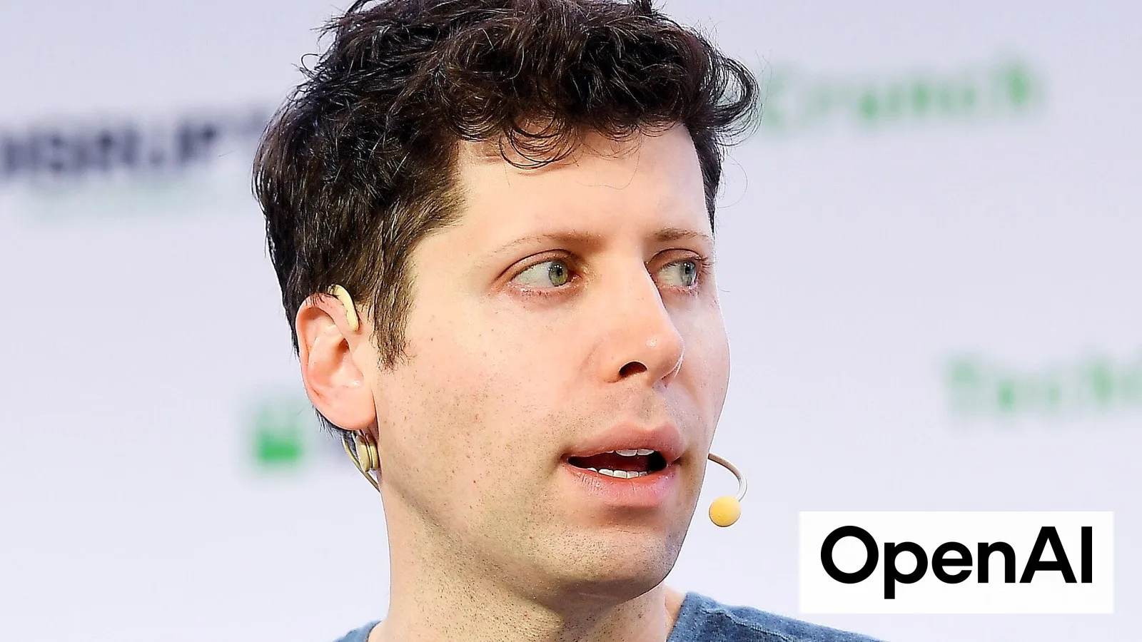 OpenAI CEO Sam Altman speaking at TechCrunch SF, with the OpenAI logo